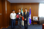 永田学長と三明康郎研究担当副学長と表彰楯を手にする松本教授(中央)